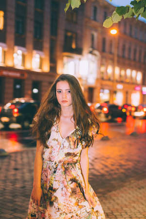 Beautiful woman in gorgeous dress against the backdrop of the city at night. Motion effect.の写真素材