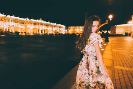Beautiful woman in gorgeous dress against the backdrop of the city at night. Motion effect.の写真素材