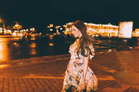 Beautiful woman in gorgeous dress against the backdrop of the city at night. Motion effect.の写真素材