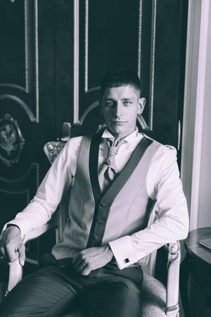 Businessman in a waistcoat and plastron sitting on a chair in the interior Suitesの写真素材