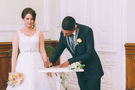 Bride and groom signing marriage license on wedding contractの写真素材