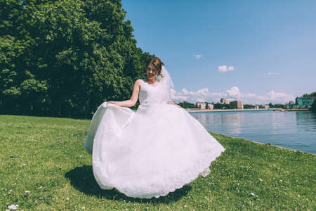 Beautiful young bride in a magnificent wedding dress spinning in nature, happiness, funの写真素材
