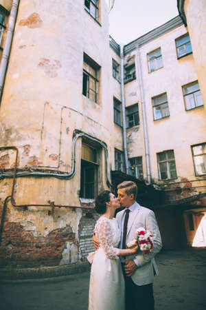The bride and groom kiss in the courtyard of old buildingsの写真素材