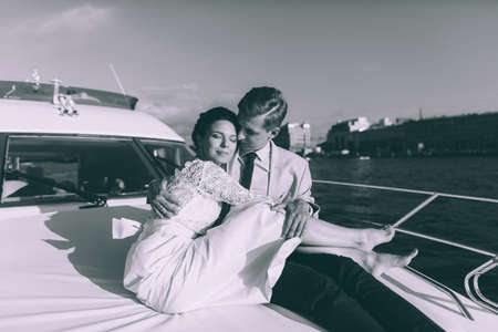 Happy bride and groom on a yacht traveling together on a warm summer dayの写真素材