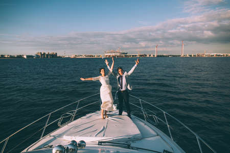 Happy bride and groom on a yacht traveling together on a warm summer dayの写真素材