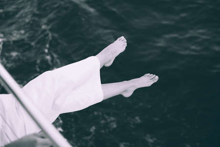 Woman holding her feet above the sea during a boat trip