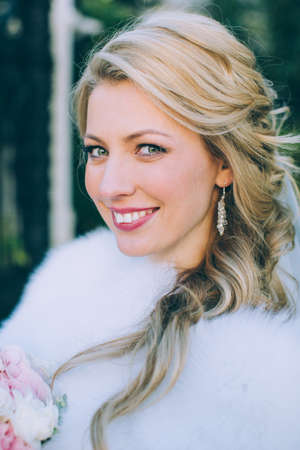 Beautiful bride with wedding bouquet of flowers roses outdoors in green park