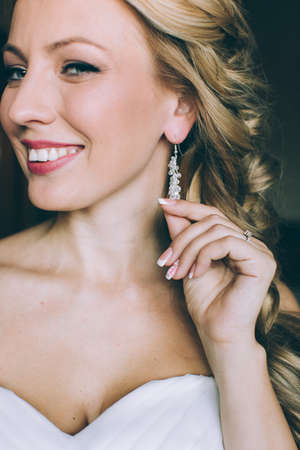 Woman putting on diamond earrings. Caucasian beauty lady trying and shopping jewelry.の写真素材