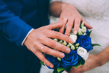bride and groom holding hands with bouquet flowersの写真素材