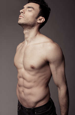 Muscular young sexy guy posing in studio in jeans and naked torsoの写真素材
