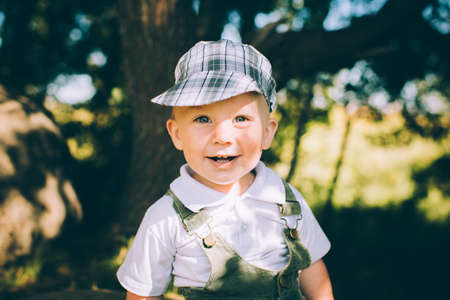 The little boy in overalls and a cap on the nature