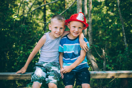 Two little boys friends sits outdoors in natureの写真素材