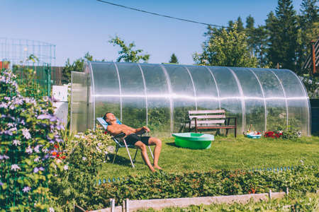 Man in a bathing suit sunbathes in a chair outdoorsの写真素材