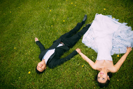 newly-married couple Lie on green grass in fieldの写真素材