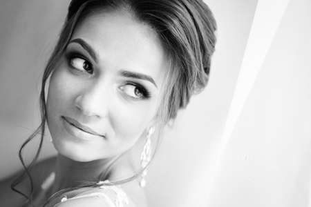 Beautiful happy bride in white silk lingerie in her bedroom in a morningの写真素材