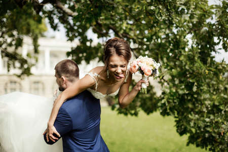 Groom carries his bride over shoulder. Outdoor.の写真素材