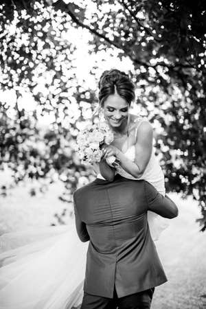 Groom carries his bride over shoulder. Outdoor.の写真素材
