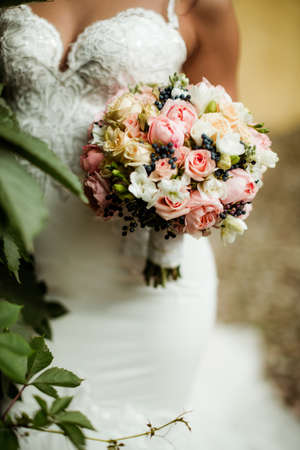 beautiful tender wedding bouquet of roses and eustoma flowers in hands of the brideの写真素材