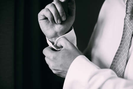 Man buttoning on the sleeve of his shirt. Zip up the cufflink. Men's style.