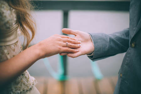 Close-up of wedding details. Groom's hand holding bride's hand. The bride's wedding ring on the finger. Wedding day.の写真素材