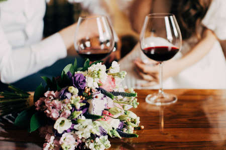 Wedding bouquet near to glass of red wineの写真素材