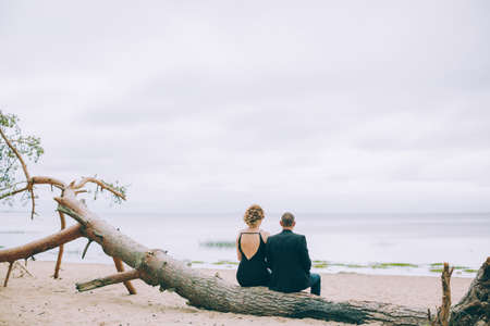 Loving couple spending leisure time together at beach sitting on sea shoreの写真素材