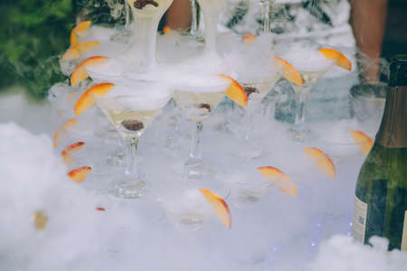 Champagne glasses. Wedding slide champagne for bride and groom outdoors. Colorful wedding glasses with champagne. Catering service. Catering bar for celebration. Beauty of bridal interior for weddingの写真素材