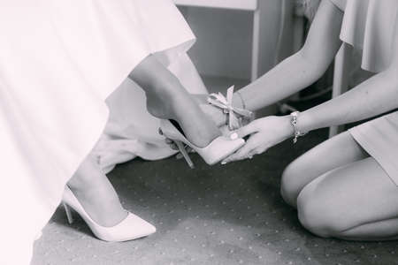bridesmaid helping bride to put on elegant shoesの写真素材