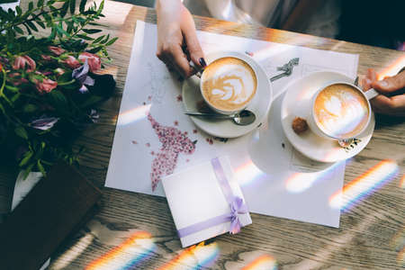 Hands of the bride and groom for a cup of coffee. Wedding bouquet on the table. Marriage concept.の写真素材