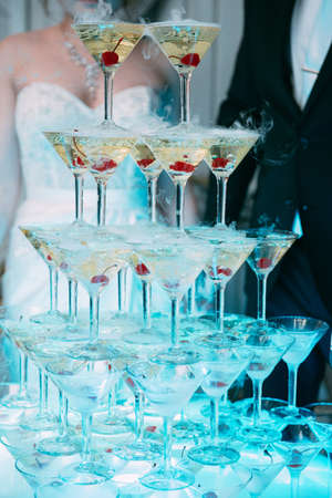 Champagne glasses. Wedding slide champagne for bride and groom. Colorful wedding glasses with champagne. Catering service. Catering bar for celebration. Beauty of bridal interior for weddingの写真素材