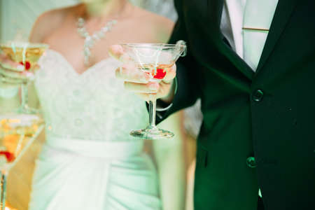 Bride and groom with glasses of champagne in his hand, focus on glasses