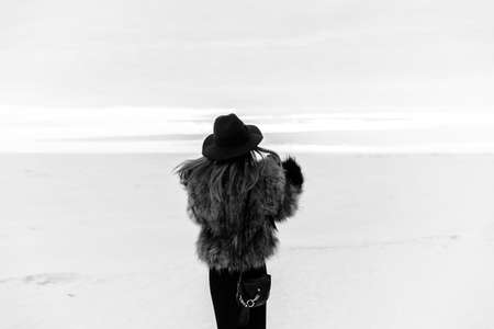Portrait of a young beautiful blonde woman with hat, in a fur coat, outside, on the snow. A good dark day with beautiful shadows - a sunny winter day, sunset.の写真素材