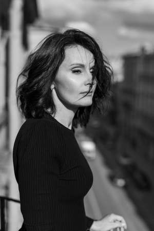 Stylish woman in black stands on the city balcony on the sunの写真素材