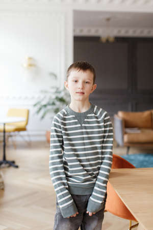 boy in a striped sweater stands in the interior of the houseの写真素材
