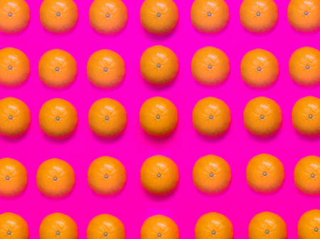 Colorful fruit pattern of fresh mandarins on a pink background. Top view