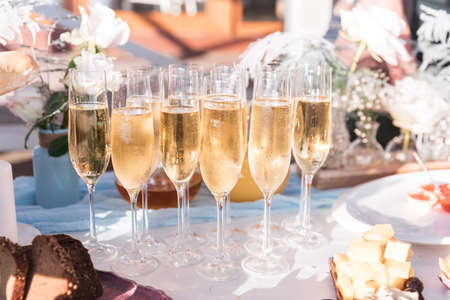 Glasses of chilled champagne stand on a table with a tablecloth for a welcome treat for guests of the eventの写真素材