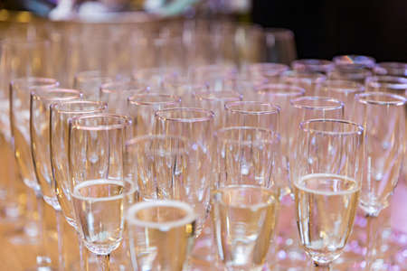 Many glasses of champagne stand on a wooden table