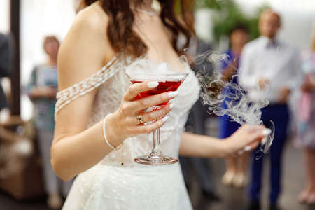 Glass of champagne with dry ice in the bride's handの写真素材