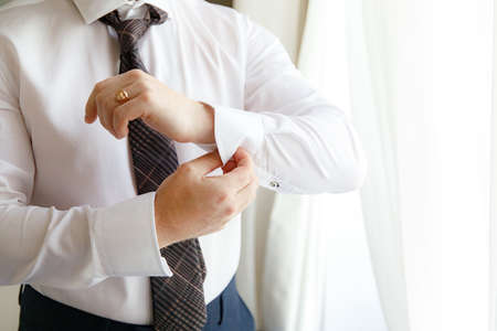 Man buttoning cuff of his shirt