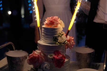 Wedding cake topped with white cream frosting will brighten up the sweet flower setting on the table. Delicious wedding event, delicious dessert ready for banquetの写真素材