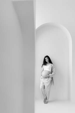 Stylish pregnant brunette girl with beige trouser suit