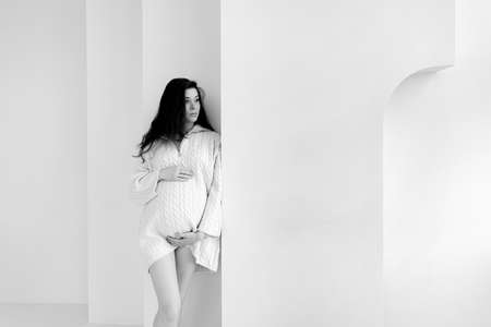 Pregnant brunette girl in an oversized knitted sweater