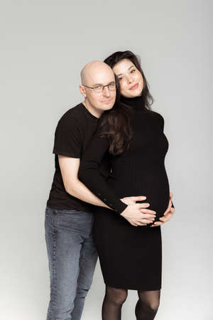 Pregnant couple in black clothes on a white backgroundの写真素材