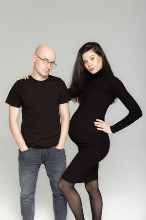 Pregnant couple in black clothes on a white backgroundの写真素材