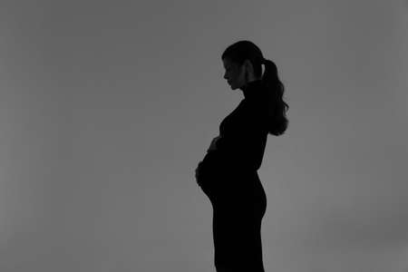 Silhouette of a pregnant girl in a black dress in a photo studioの写真素材