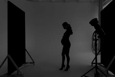 Silhouette of a pregnant girl in a black dress in a photo studioの写真素材