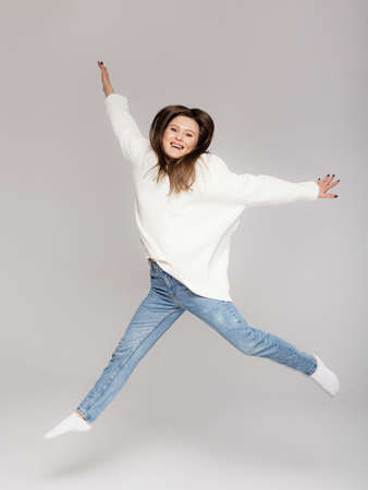 Girl in light jeans and a white oversized sweater on a gray backgroundの写真素材