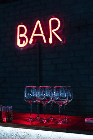 Glasses on bar neon sign backgroundの写真素材