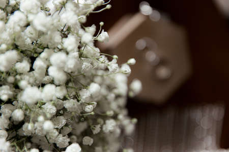 Wedding rings lie on a wooden box next to the bride's bouquetの写真素材