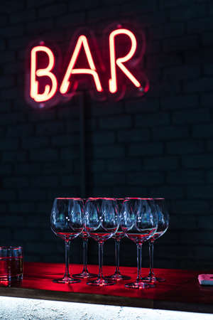 Glasses on bar neon sign backgroundの写真素材